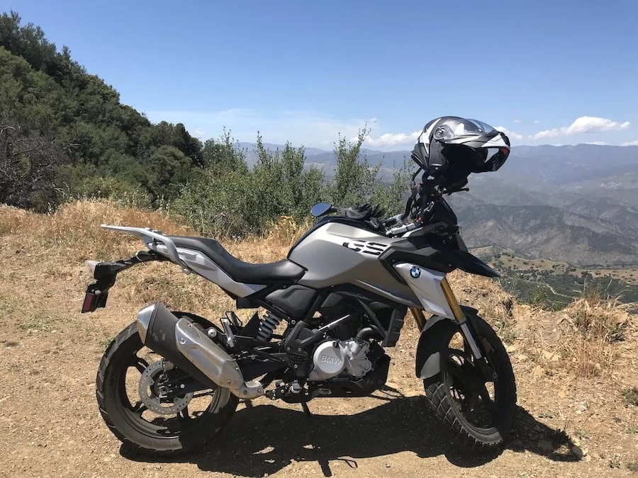 A BMW GS motorcycle parked on a dirt overlook above a mountain valley