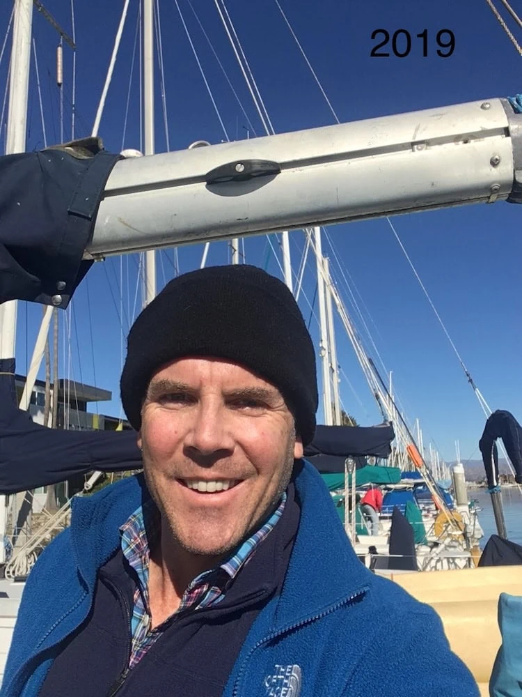 Robert Lawrence in a beanie and fleece aboard a sailboat at a marina, 2019